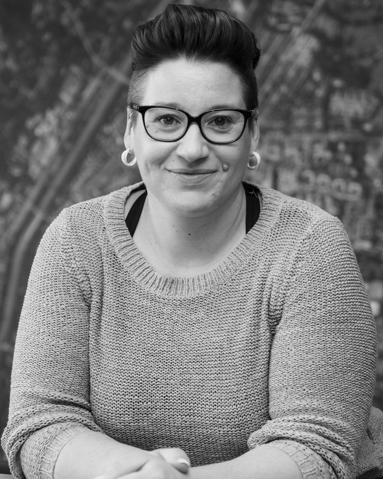 Regina, Managing Director of SAM Innovate, smiling at a wooden table in front of an aerial map of Munich