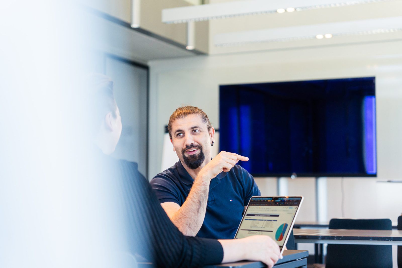 Hüseyin Torun im Gespräch am Besprechungstisch, vor ihm ein aufgeklappter Laptop
