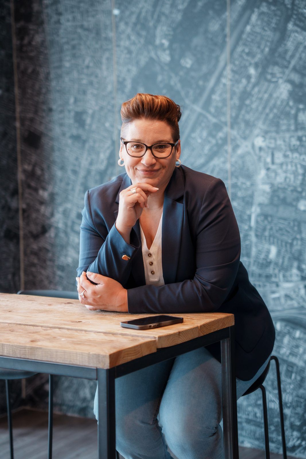 Regina Maria Zeller of SAM Innovate at a wooden table in front of an aerial map of Munich