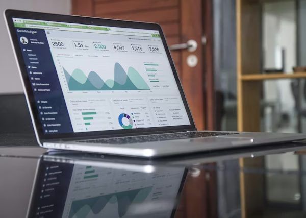 Laptop mit Statistik-Dashboard auf einem dunklen Glastisch